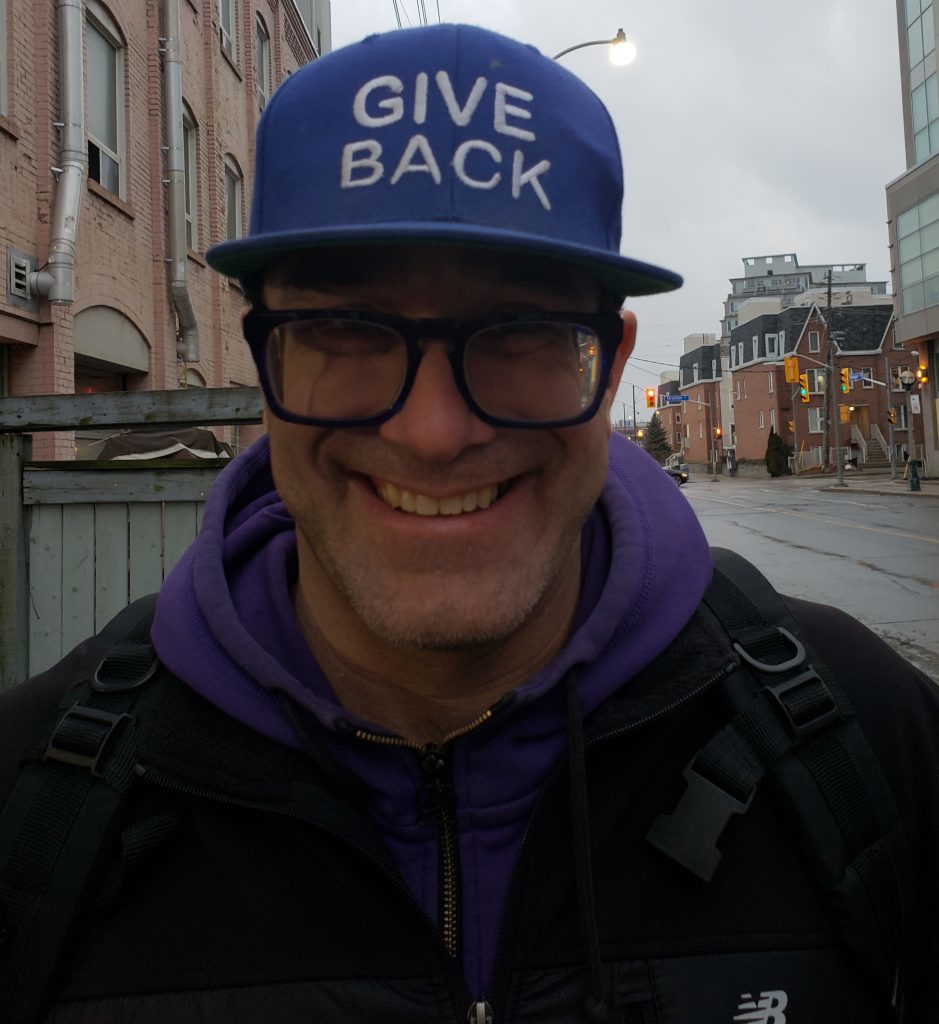 Jagger Long smiles while wearing a purple hat that says "give back".