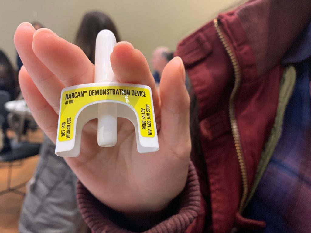 A student holds up a practise naloxone administration device.
