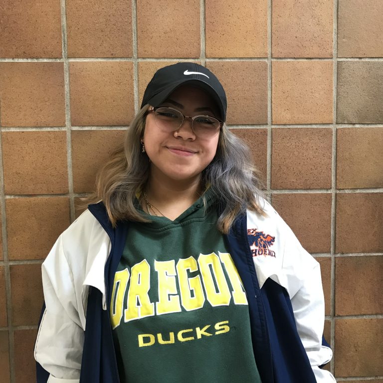 Filipino girl wearing a black hat, white jacket on top of a green sweater that says Oregon Ducks