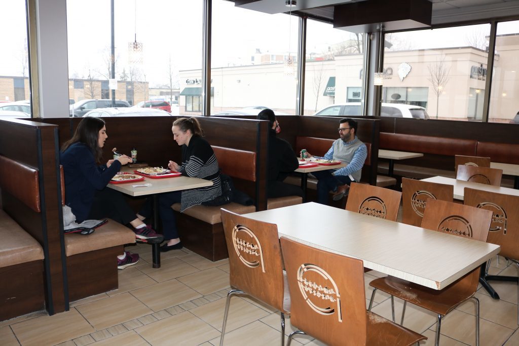 People enjoying their meals at booths and tables.