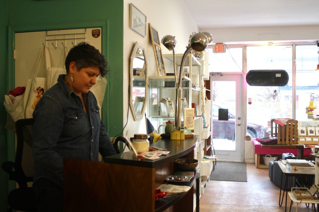 Cheryl Gudz doing on her laptop behind the checkout counter inside her store.