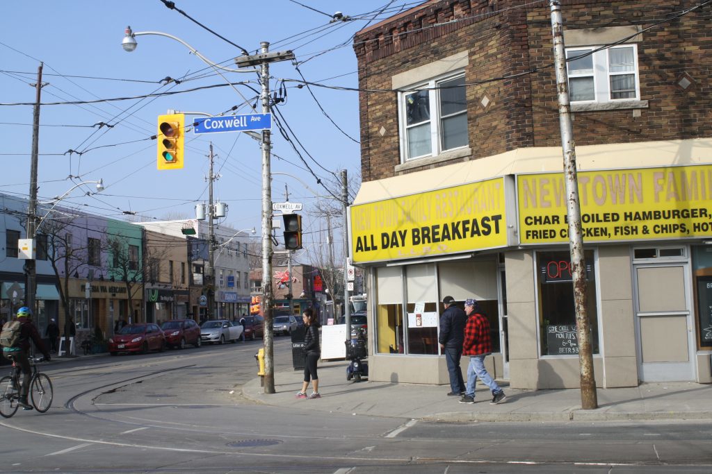 Corner of the street and yellow restaurant awning that reads New Town Family Restaurant.