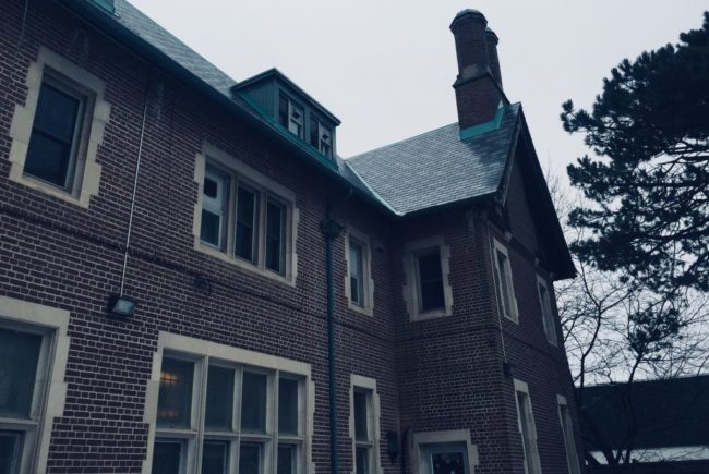 Red brick house that has many windows. The photo is in a blue/grey hue.