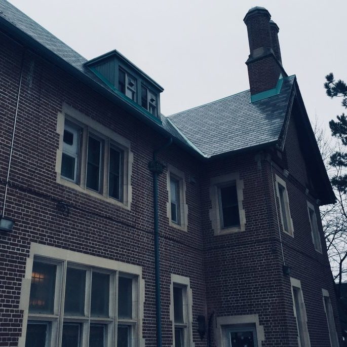 Red brick house that has many windows. The photo is in a blue/grey hue.