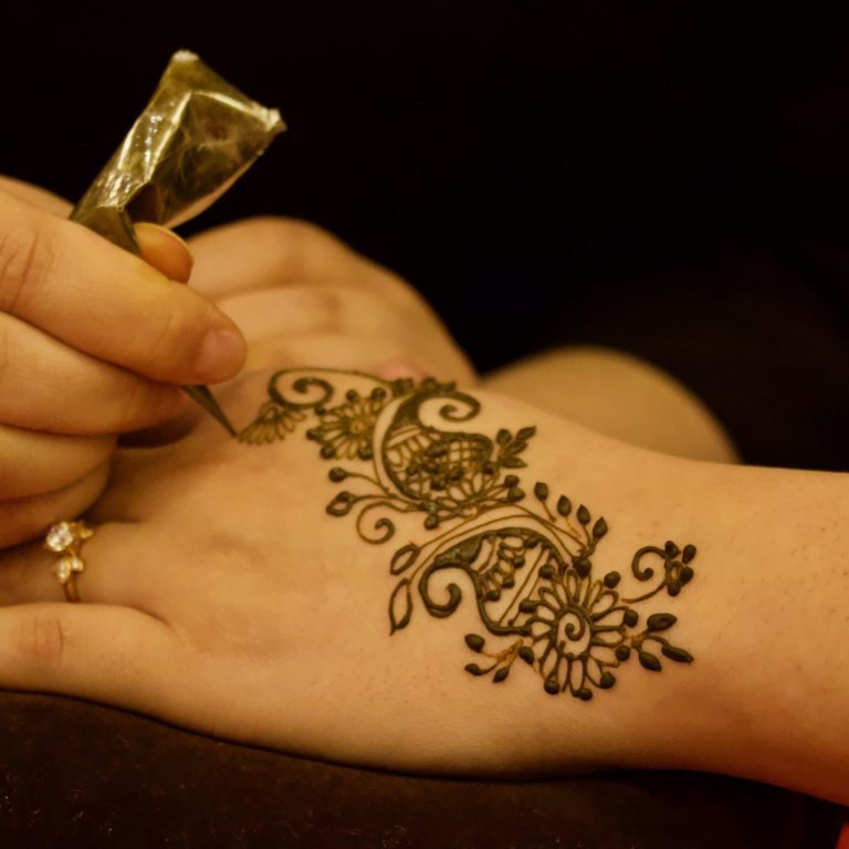 Person putting henna on the hand of a client.