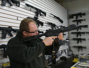 A man point an airsoft gun at the ceiling to check that it is empty.