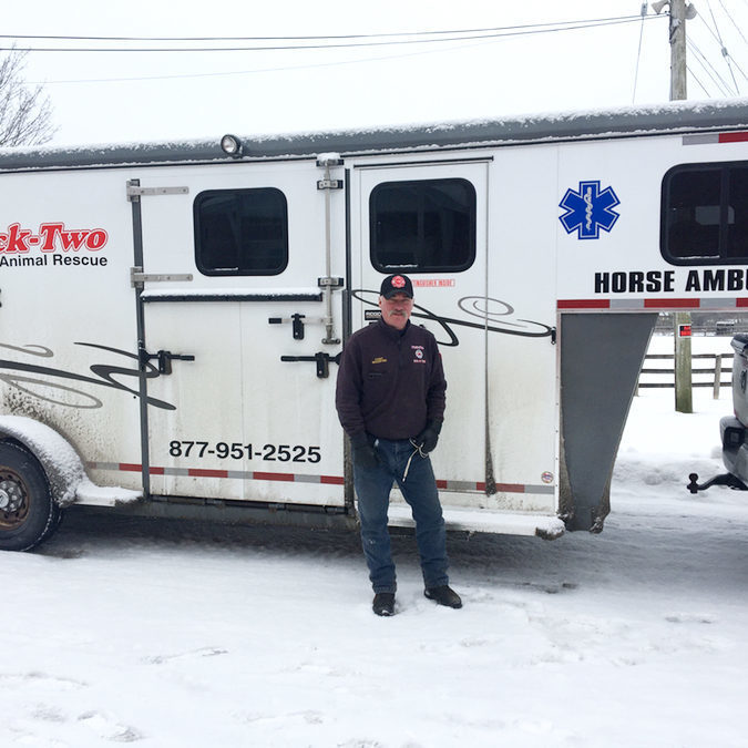 Man standing in front of a trailer that says "Horse Ambulance" and "Tack-Two, Large Animal Rescue" on it.