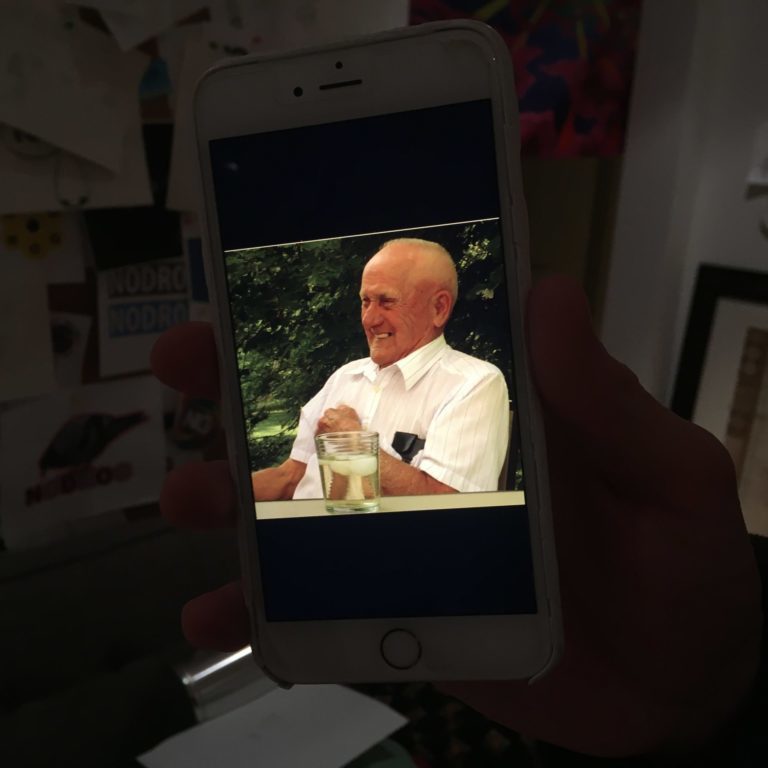 2 Photo taken on an iphone of a person laughing. They are sitting outside near plenty of green trees.