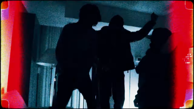 Poster of three people encased in shadow. The image is highly filtered with a stark red and blue contrast.