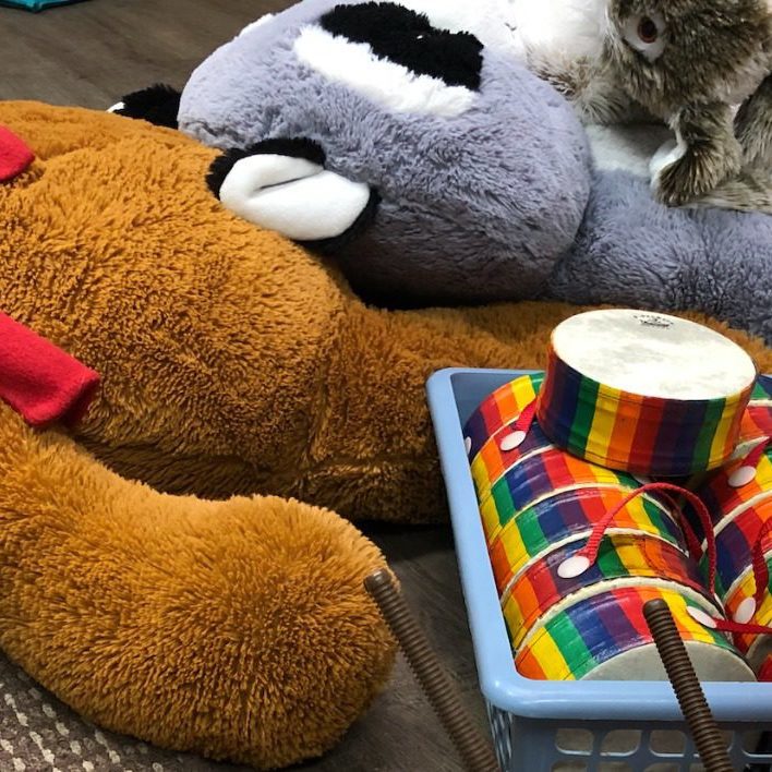 Children's toys lying on the ground. There are stuffed toys, drum sets, and art supplies.