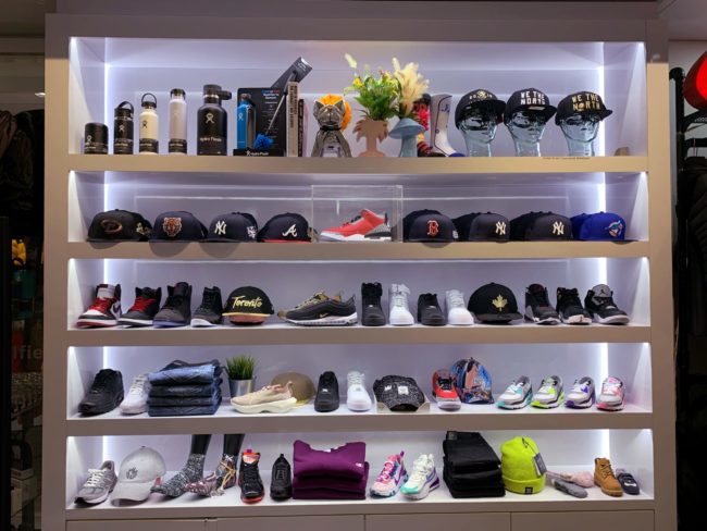 a light up five tiered shelf that showcases different clothing items. There are shoes, clothing items, hats, and water bottles.