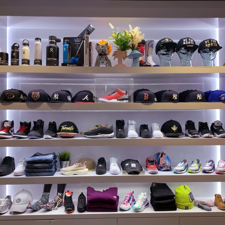 a light up five tiered shelf that showcases different clothing items. There are shoes, clothing items, hats, and water bottles.