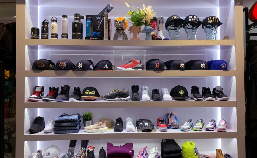 a light up five tiered shelf that showcases different clothing items. There are shoes, clothing items, hats, and water bottles.