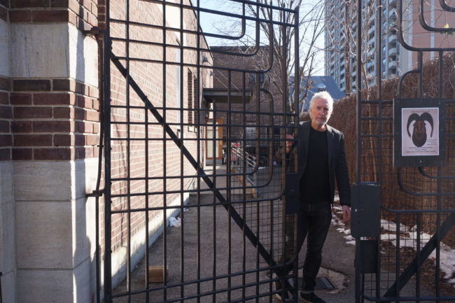 Man in a black outfit opening gates.