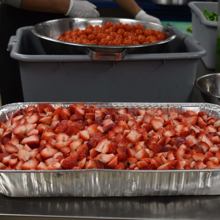 Aluminum Container holding cut up strawberries.