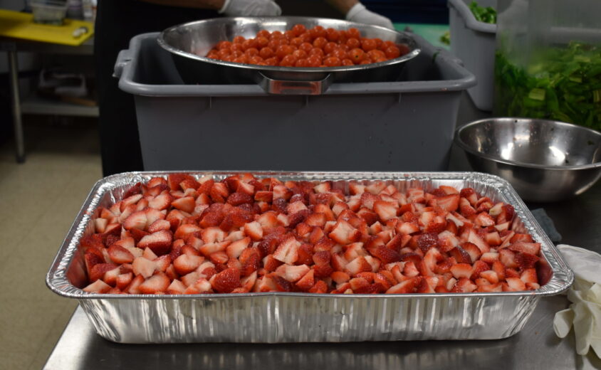 Aluminum Container holding cut up strawberries.
