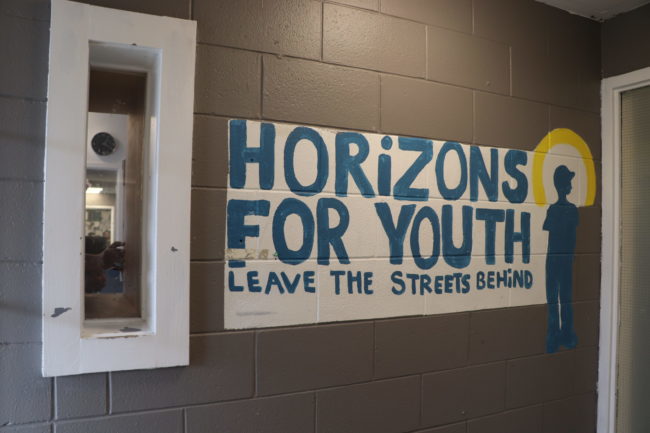 Painted sign on a grey brick wall that says "Horizons For Youth, Leave the Streets Behind."
