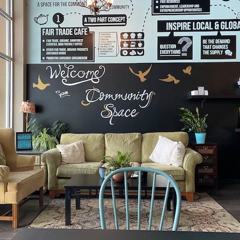 A small lounge area at the front of a store. The furniture is a green/yellow colour, while the walls are black and sky blue. The wall reads 'Welcome to your community space.'