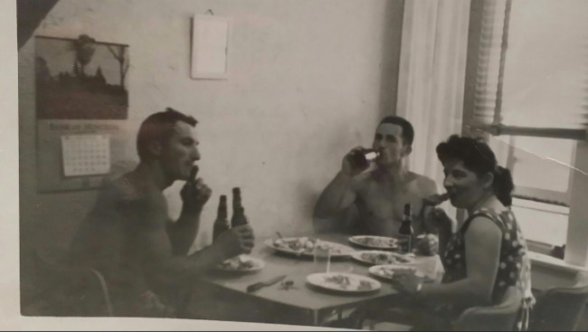 Black and white photo if a family sitting down for a meal together.