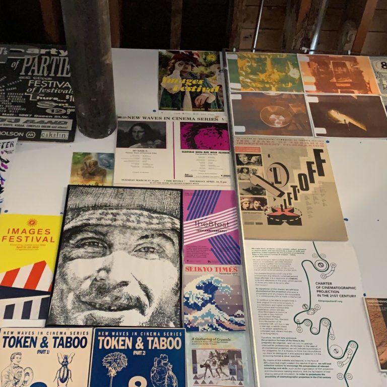 Wall decorated with posters. The posters all have varying aesthetics and advertise different things, although they are purely decorative now.