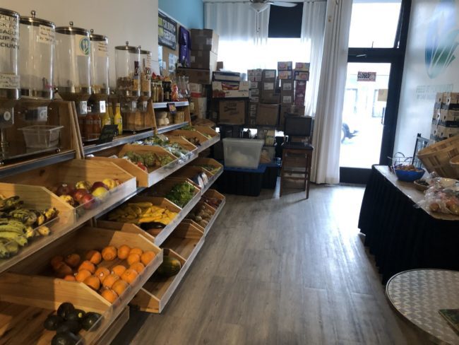 Food in wooden bins. There are cardboard boxes at the back and lines of cereal dispensers against the wall.