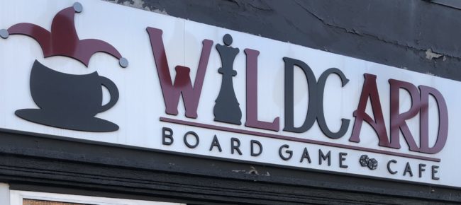 Sign for Wildcard Board Game Cafe. The sign is red, black, and white.
