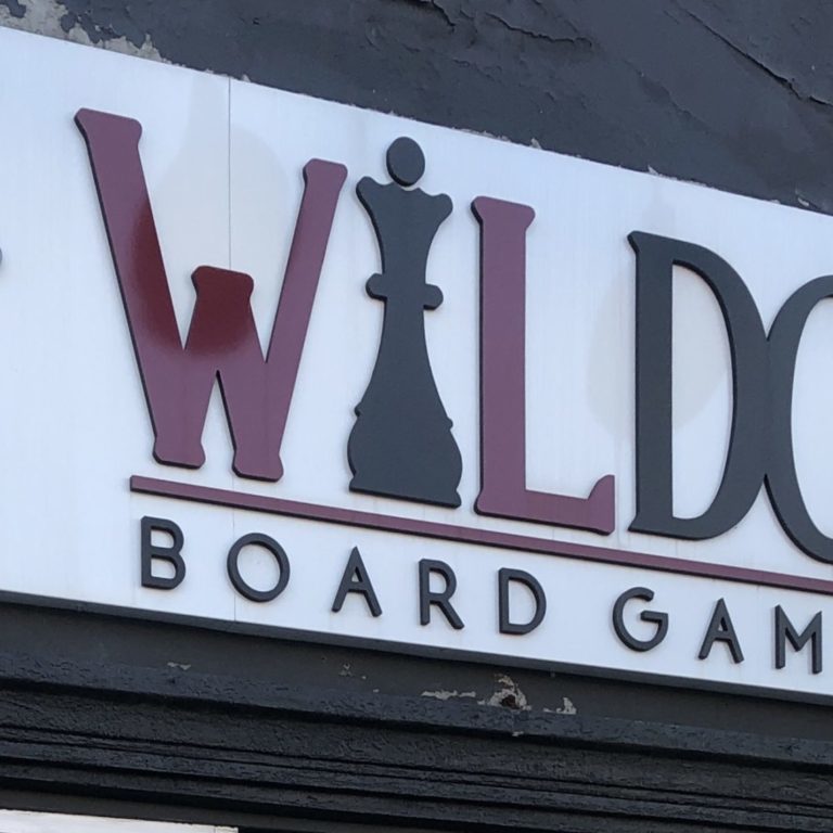 Sign for Wildcard Board Game Cafe. The sign is red, black, and white.