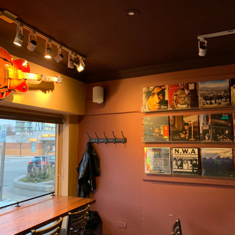 Sitting area with a guitar on the wall. There is also a wall of Vinyl CD cover art.