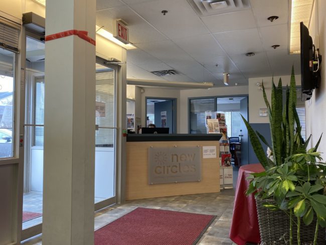 The entrance to new circles. There is a reception desk and several large plants right in the entryway.