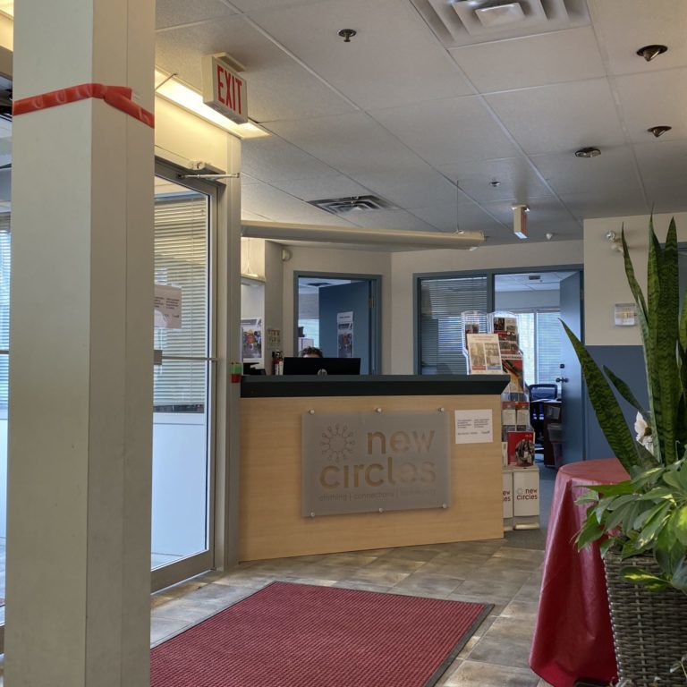 The entrance to new circles. There is a reception desk and several large plants right in the entryway.