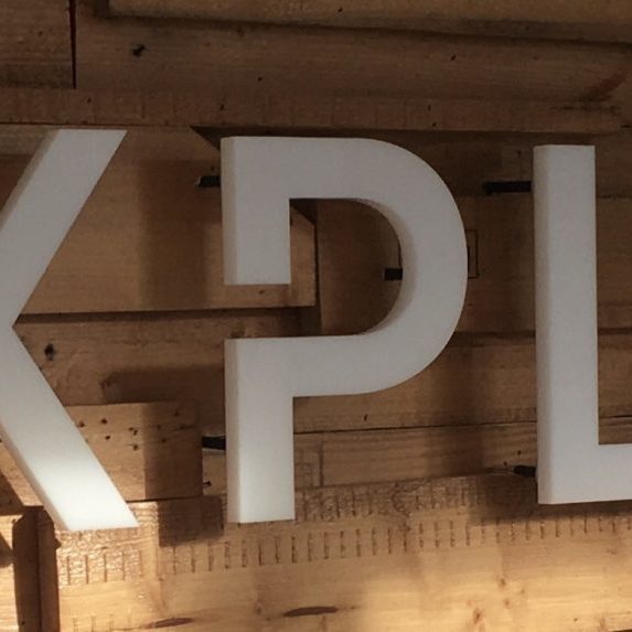 Cover Image; Explore Printing a banner image of the explore printing logo. The background wall is wood panelling, and the 'e' in explore is filled with succulents.