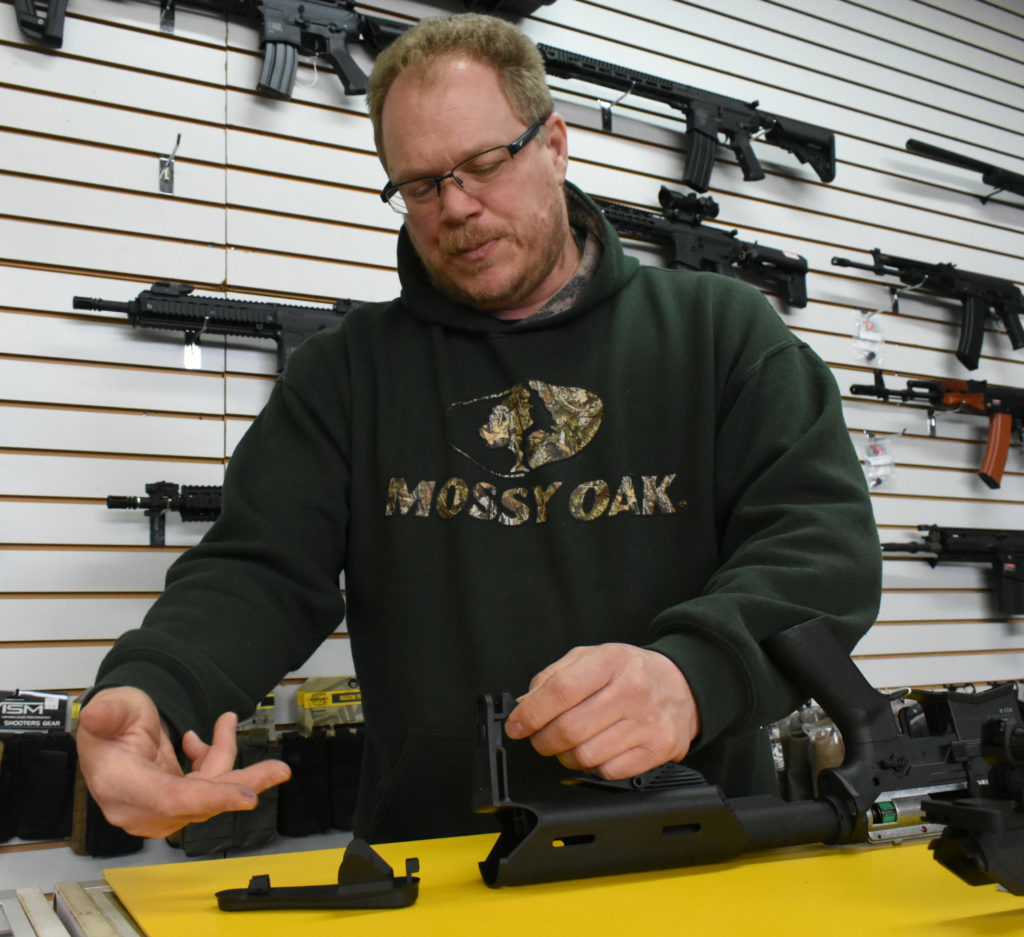 A man putting a cover on a hollow gun buttstock.