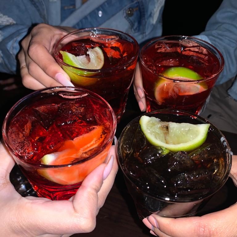 People holding drinks with limes in them. The background is dark as though the image has been taken with flash.
