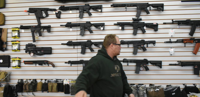Man with wall of replica guns