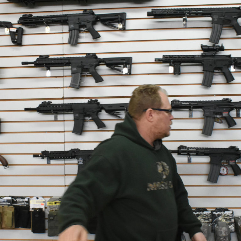 new header Man with wall of replica guns