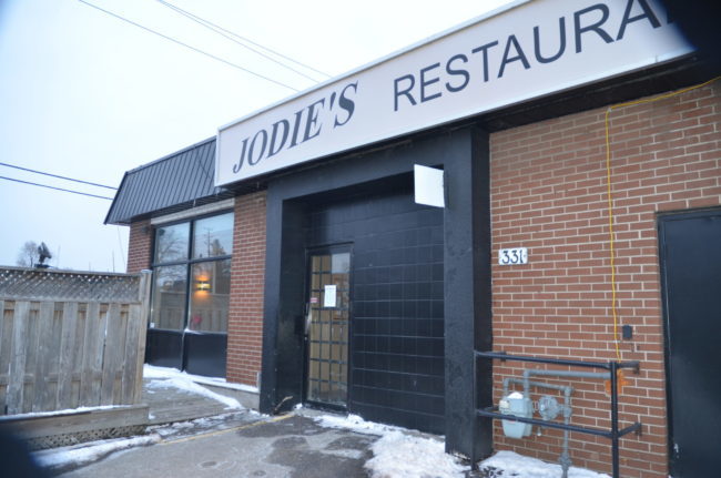 An exterior image of Jodie's Restaurant, which is a red brick building and a black tile door.