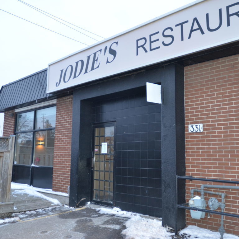 store front An exterior image of Jodie's Restaurant, which is a red brick building and a black tile door.