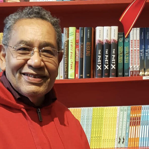 Miguel San Vicente in front of a red bookshelf.