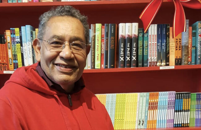 Miguel San Vicente in front of a red bookshelf.