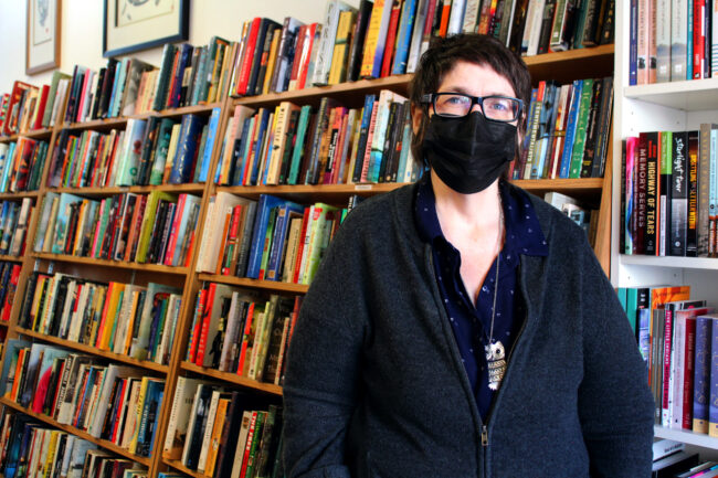 Woman in front of packed bookshelves.