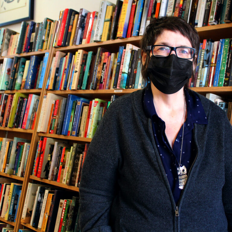 Woman in front of packed bookshelves.