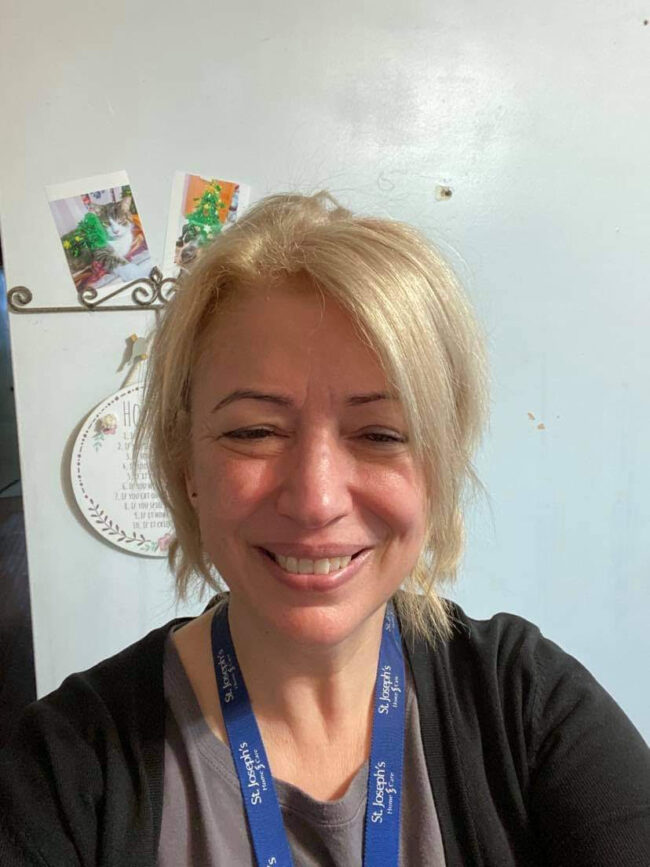 Blonde woman wearing a blue lanyard.