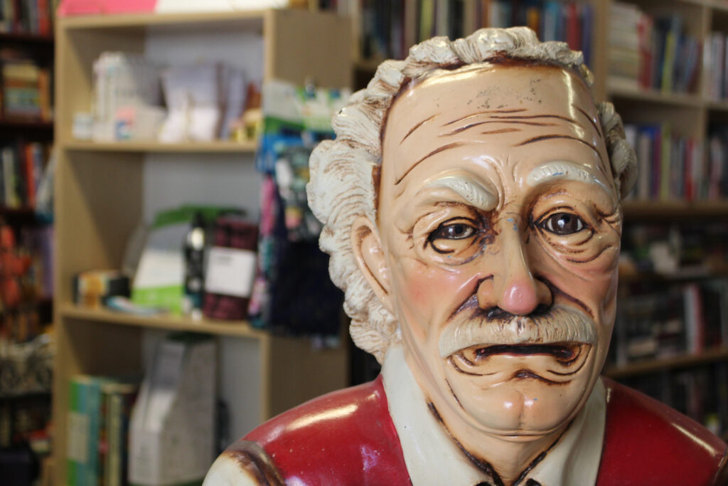 Close-up photo of the face of the old man statue. His face is wrinkled and some paint is chipping off. 