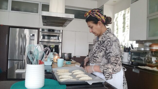 Woman in the kitchen baking crossiants.