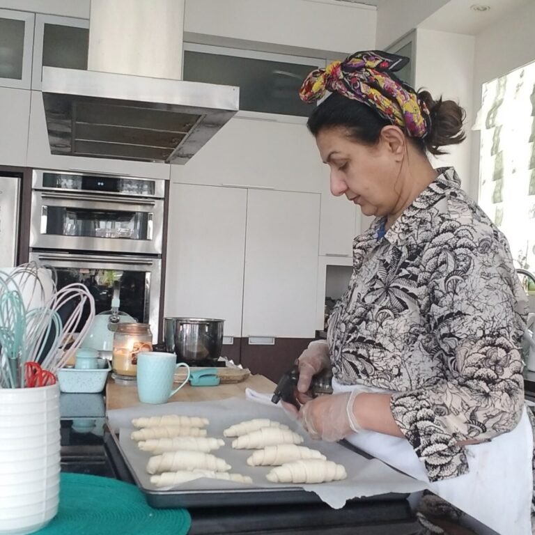 Woman in the kitchen baking crossiants.