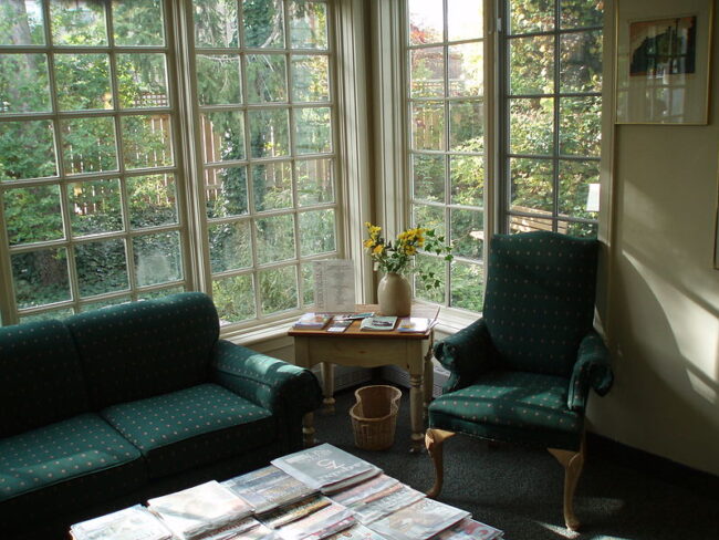 Sitting area with a green couch and green armchair in front of a huge window.