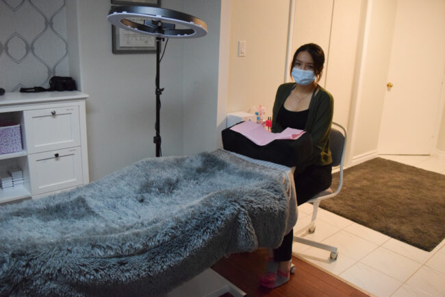 Woman sitting by a lash bed.