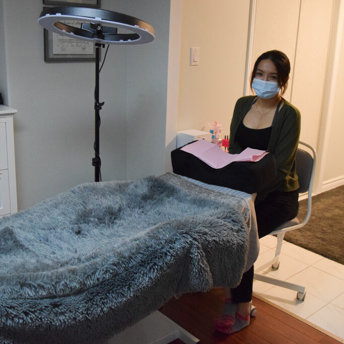 Woman sitting by a lash bed.