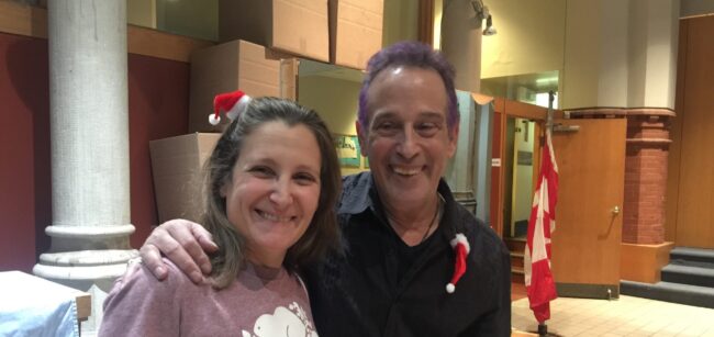Man and woman standing side by side with small Santa hat accessories.