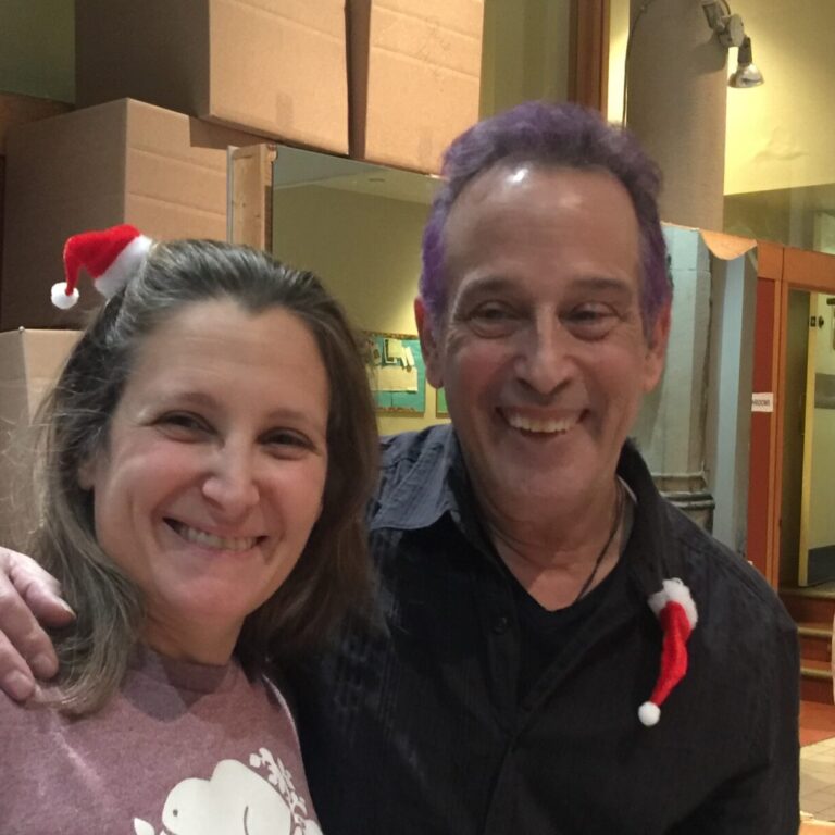 Man and woman standing side by side with small Santa hat accessories.